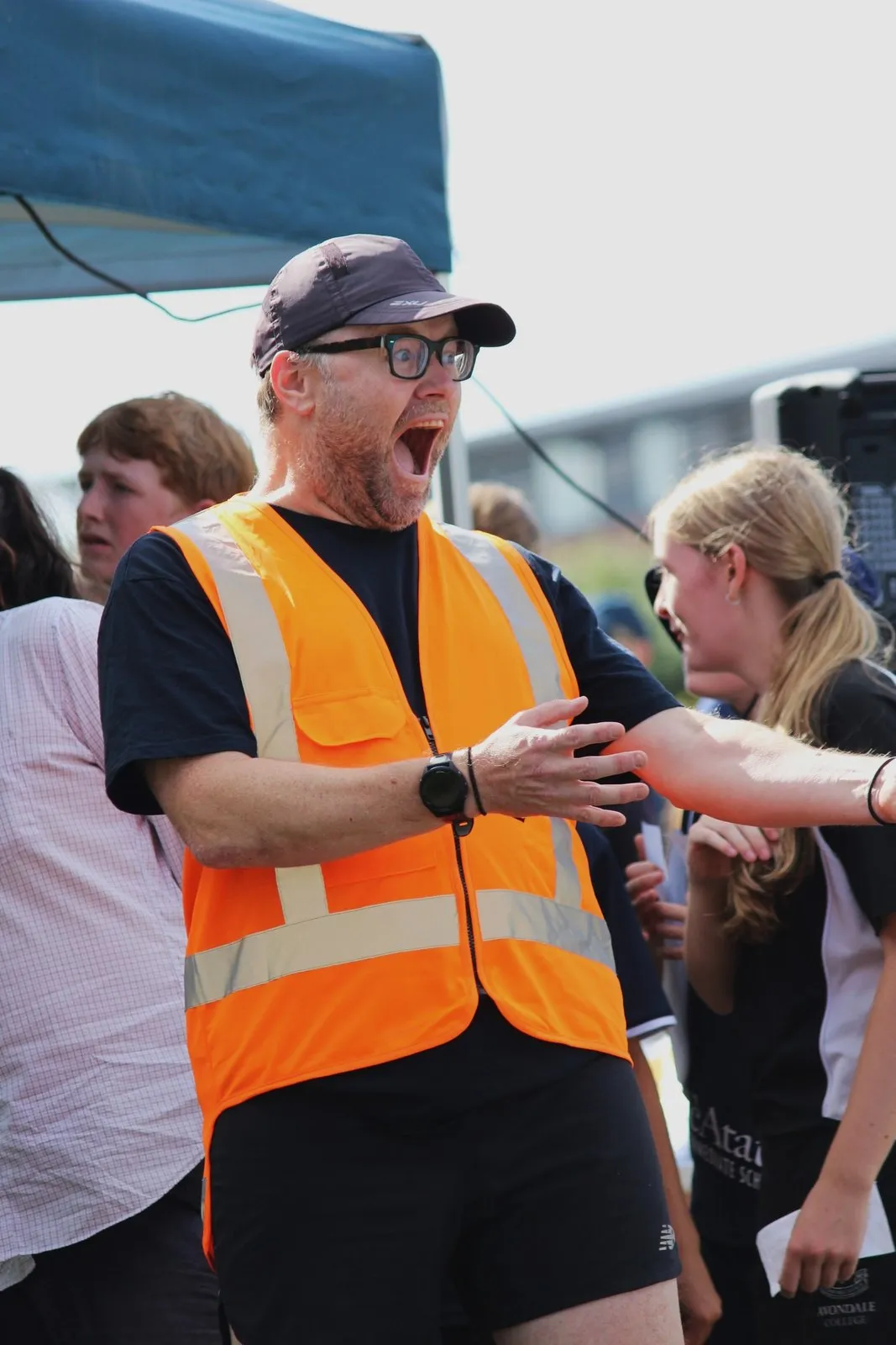 Neill in a hi-vis vest, mouth open in delight, reacting to a student at the finish of a Sprint Series event